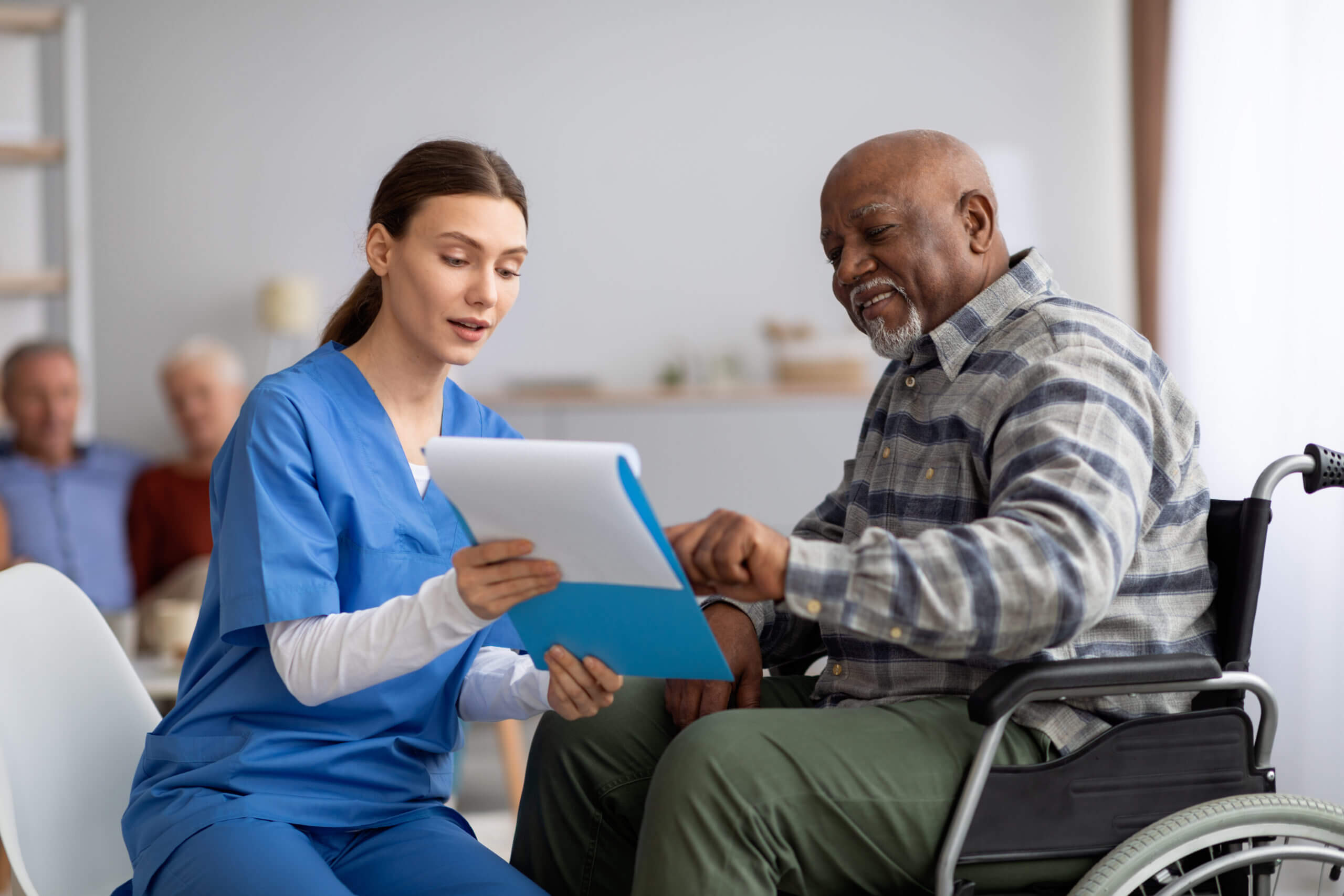 senior caregiver reading form to a wheelchair patient 